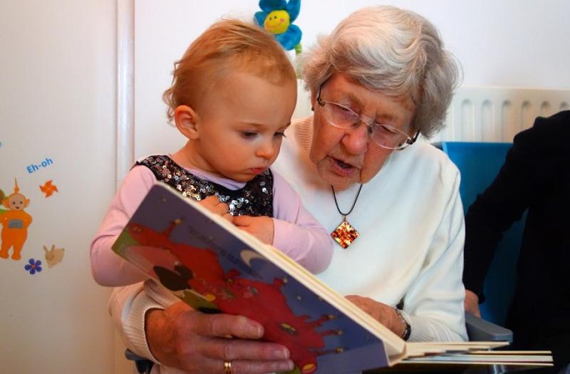 na zdjęciu dziecko czytające książkę z babcią