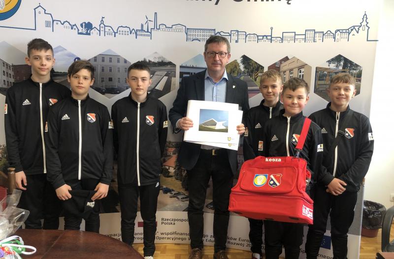 Na zdjęciu piłkarze z CKS Zduny pokazują nową torbę, a burmistrz projekt nowych szatni