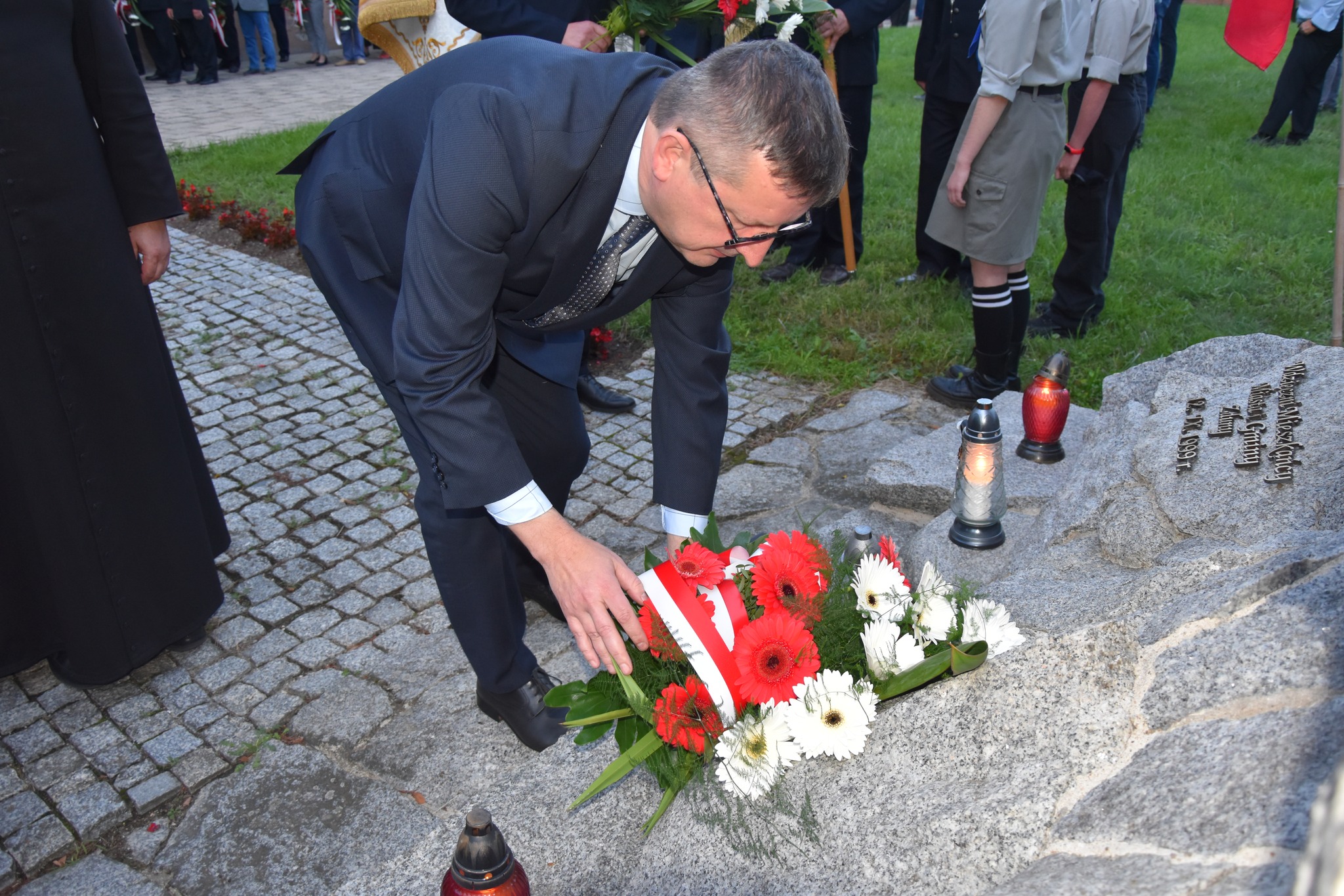 Burmistrz Zdun składa wiązankę kwiatów przy pomniku na meantrzu parafialnym